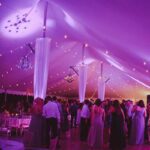 Inside of a frame tent decorated with lights